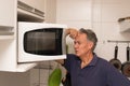 Senior man in his kitchen looking into his microwave Royalty Free Stock Photo