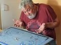 Senior man on his own angry doing a jigsaw puzzle.