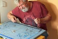 Senior man on his own difficult doing a jigsaw puzzle. Royalty Free Stock Photo