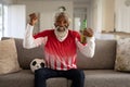 Senior man holding beer bottle cheering while watching sports on TV Royalty Free Stock Photo