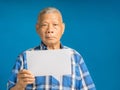 Senior man holding a blank speech bubble while standing on a blue background Royalty Free Stock Photo