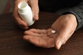 Senior man holding bottle and pill at table Royalty Free Stock Photo
