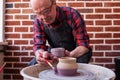 Senior man holding a brush, painting on a ceramic using potter wheel. Royalty Free Stock Photo