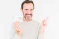 Senior man holding five pounds bank note over isolated background very happy pointing with hand and finger to the side