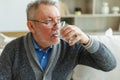 Senior man holding glass drinking fresh water at home. Mature old senior thirsty grandfather takes care of his health