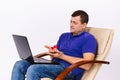 Senior man holding a hearing aid and a red heart in front of a laptop camera. Glad to the gift in online life. White Royalty Free Stock Photo