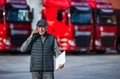 Worker talking on phone in front of trucks