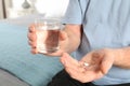 Senior man holding pill and glass of water indoors Royalty Free Stock Photo