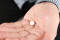 Senior man holding pill in hand Royalty Free Stock Photo