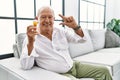 Senior man holding pills smiling and confident gesturing with hand doing small size sign with fingers looking and the camera Royalty Free Stock Photo
