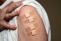 Senior man holding up shirt showing four covid-19 vaccine injections Royalty Free Stock Photo