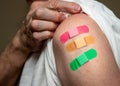 Senior man holding up shirt showing three covid-19 vaccine injections Royalty Free Stock Photo