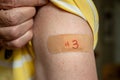 Senior man holding up shirt after third covid-19 vaccine injection Royalty Free Stock Photo