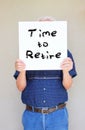Senior man holding white canvas board in front of his face with the phrase time to retire Royalty Free Stock Photo