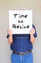 Senior man holding white canvas board in front of his face with the phrase time to retire