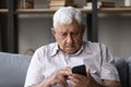 Senior man holds smartphone staring at screen feels concerned Royalty Free Stock Photo