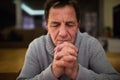 Senior man at home praying, hands clasped together Royalty Free Stock Photo