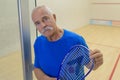 Senior man on indoor court holding raquet