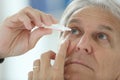Senior man injecting serum in his eyes Royalty Free Stock Photo