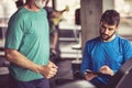 Senior man jogging on treadmill, personal trainer writing on file.