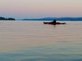 Solo kayaker on the ocean as the sun set casts purple shades across the tranquil waters.