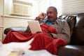 Senior Man Keeping Warm Under Blanket With Photograph