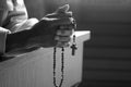 Senior man kneel, holding wooden rosary beads in hands with Jesus Christ holy cross crucifix in the church. Natural light Royalty Free Stock Photo