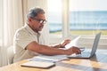 Senior man, laptop and documents in budget planning, schedule payment or checking bills at home. Mature male person Royalty Free Stock Photo