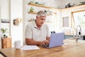 Senior man, laptop and working in kitchen on retirement plan, budget and expenses at home. Elderly male typing on Royalty Free Stock Photo