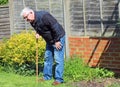 Senior man leaning on waking stick or cane.