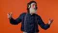 Senior man listening music on headphones dancing disco fooling around having fun gesticulating hands