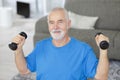 senior man listing weights at home Royalty Free Stock Photo