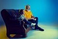 Senior man and little girl, grandfather watching TV with his granddaughter over blue background in neon light Royalty Free Stock Photo