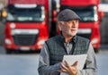 Senior man logistician standing in front of trucks