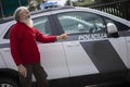 Senior man with a long gray beard points a finger at a police car Royalty Free Stock Photo