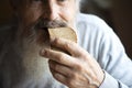 Old sad man with a long gray beard sitting by the table and eating bread Royalty Free Stock Photo