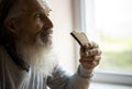 Old sad man with a long gray beard sitting by the window and eating bread Royalty Free Stock Photo