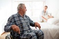 Senior man looking at doctor adjusting bed while sitting on wheelchair Royalty Free Stock Photo