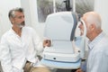 Senior man looking into eye testing machine Royalty Free Stock Photo