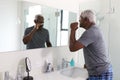 Senior Man Looking At Reflection In Bathroom Mirror Wearing Pajamas Brushing Teeth Royalty Free Stock Photo