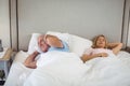 Senior man lying on bed and covering his ears with pillow Royalty Free Stock Photo