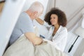 Senior man lying on bed talking to grand daughter Royalty Free Stock Photo