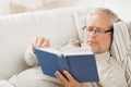 Senior man lying on sofa and reading book at home Royalty Free Stock Photo