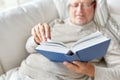 Senior man lying on sofa and reading book at home Royalty Free Stock Photo