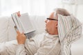 Senior man lying on sofa and reading book at home Royalty Free Stock Photo