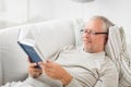 Senior man lying on sofa and reading book at home Royalty Free Stock Photo