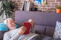 Senior man lying on sofa and reading book at home - retired, leisure and people concept Royalty Free Stock Photo