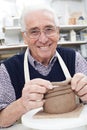 Senior Man Making Coil Pot In Pottery Studio
