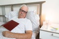 Senior man male bed home tired sick ill alone retired resting sleeping book Royalty Free Stock Photo