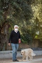 senior man in mask with his pet dog on street because of air pollution and epidemic in city. Protection against virus Royalty Free Stock Photo